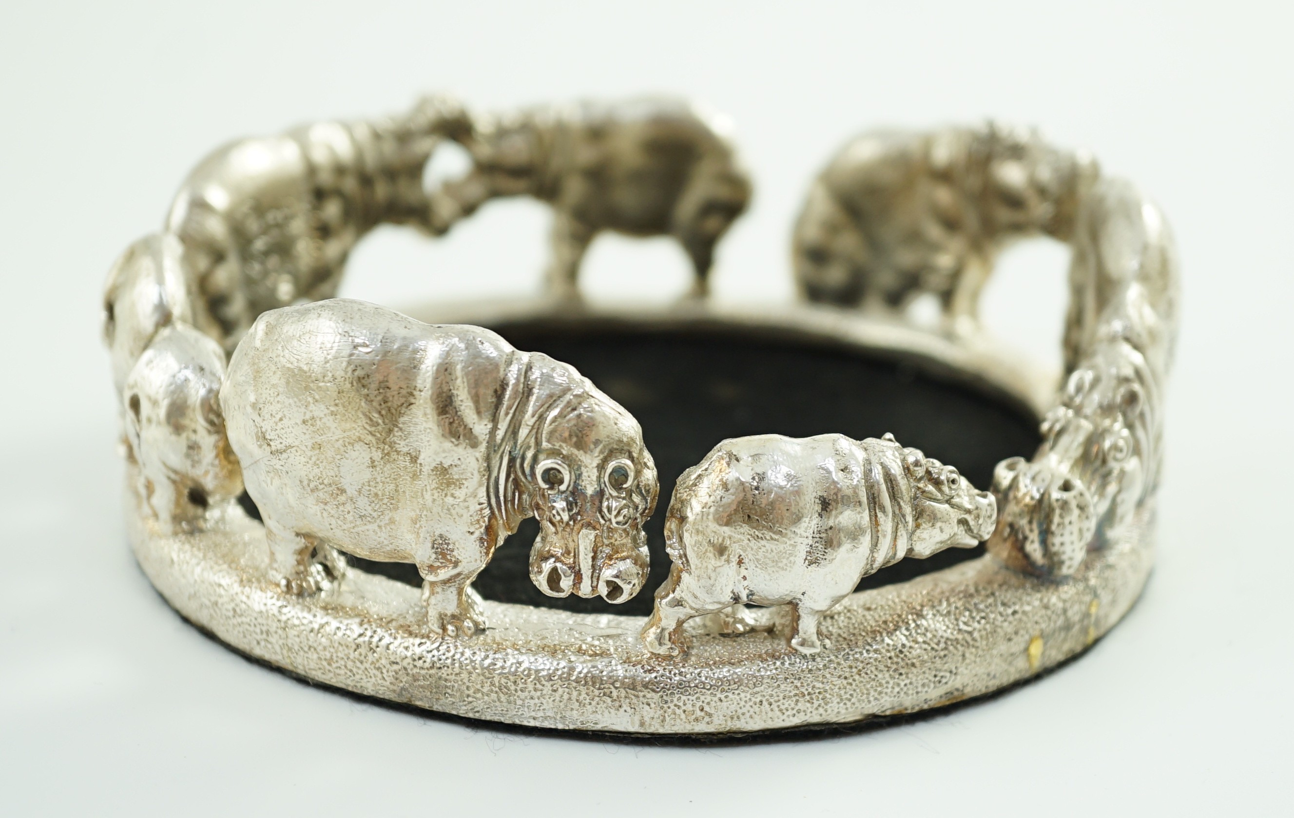 Patrick Mavros - A modern novelty silver bottle coaster, modelled as a continuous bloat of hippopotami, in various positions